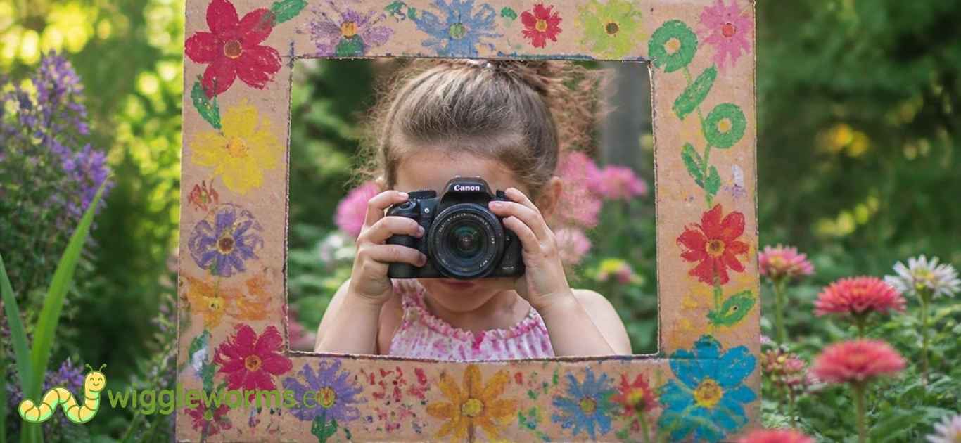 Child taking a photo of garden plants through a cardboard frame